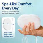 Hand holding a white cleansing pad with dimensions (5 inches tall x 3 inches wide x 1 inch thick) and text about spa-like comfort, every day.