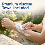 Hands using a white viscose microfiber towel to dry a forearm with rich lather in an outdoor setting. Headline: Premium Viscose Towel Included – True No-Rinse Clean With Zero Sticky Residue.