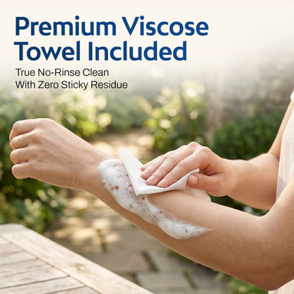 Hands using a white viscose microfiber towel to dry a forearm with rich lather in an outdoor setting. Headline: Premium Viscose Towel Included – True No-Rinse Clean With Zero Sticky Residue.